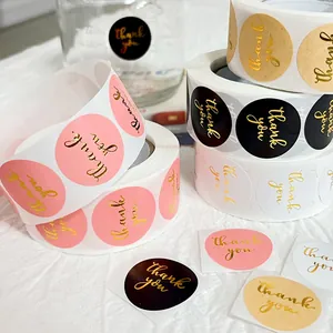 Close-up of assorted gold foil thank you stickers in pink, black, and kraft colors