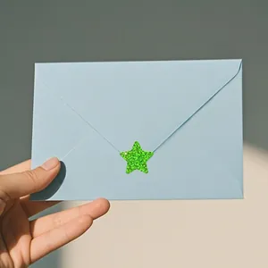 Detailed view of a sparkling green star-shaped sticker sealing a light blue envelope