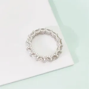 Close-up view of a classic silver eternity ring with round sparkling moissanite stones on white.