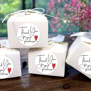 Close-up of 2.5cm circular Thank You stickers with a red heart on white gift boxes.