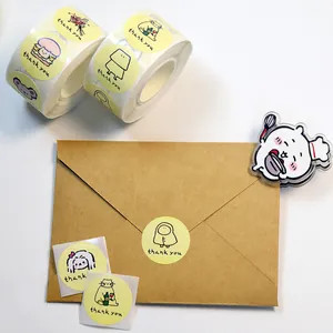 Primo piano di simpatici adesivi di ringraziamento su rotoli e busta di carta kraft