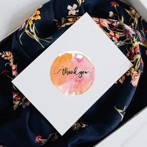 Gros plan d'un autocollant rond 'thank you' aquarelle utilisé pour sceller un cadeau