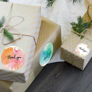 Vue détaillée d'autocollants aquarelle 'Thank You' sur des boîtes cadeaux emballées.