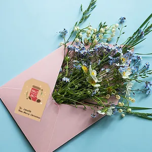 Gros plan d'une étiquette de Noël en kraft avec motif de chaussette sur enveloppe rose