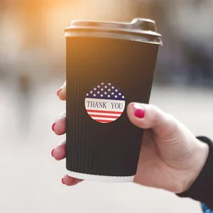 Close-up view of an American flag 'Thank You' sealing sticker on a black coffee cup