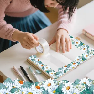Daisy pattern PET decorative tape being applied to a stationery journal notebook page.
