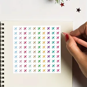 Vista dettagliata di 100 mini adesivi colorati con aerei su un taccuino per diari di viaggio