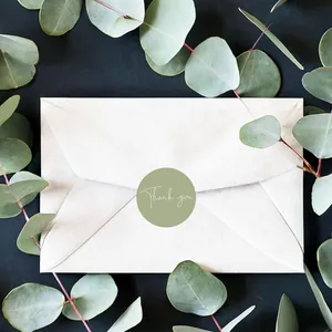 Detail of a one-inch green round Thank You sticker sealing a white paper envelope