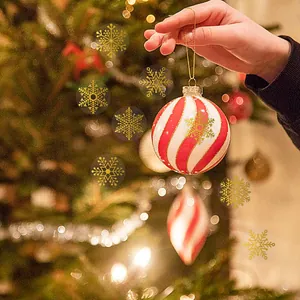 Close-up van goudfolie sneeuwvlok stickers aangebracht op een rood-witte kerstbal ornament