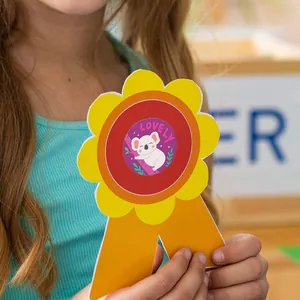 Detail of a cute koala reward sticker on a handmade flower award ribbon held by a child.