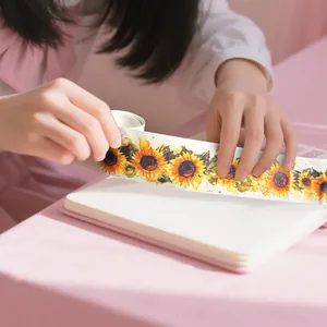 Detailopname van washi-tape met aquarel zonnebloemen aangebracht op een notitieboek