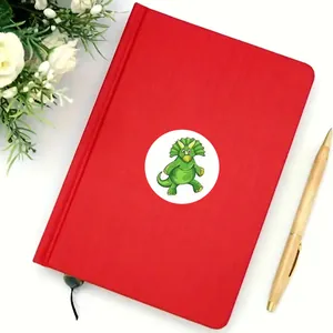 Close-up of a green triceratops reward sticker on a red notebook cover
