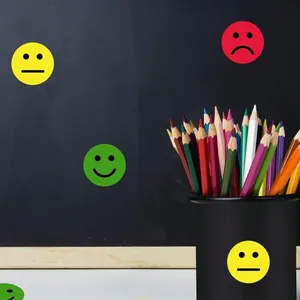 Colorful happy and sad emoji stickers applied on a classroom chalkboard and pencil holder