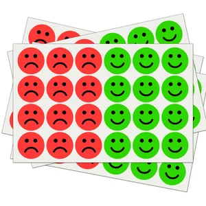 Detailed macro view showing red sad and green happy face emoji reward stickers on sheets