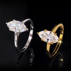 Nahaufnahme von silbernen und goldenen Moissanit-Ringen im Marquise-Schliff auf Schwarz.