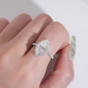 Vista detallada de un anillo de compromiso de moissanite marquise con halo en una mano