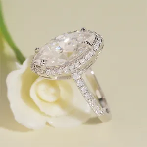 Primer plano de un anillo de compromiso de moissanita marquesa con un halo de piedras
