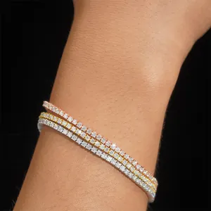 Detail view of three shimmering moissanite tennis bracelets on wrist in mixed gold finishes