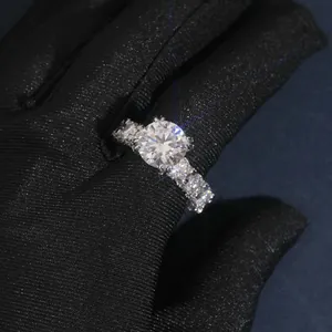 Primer plano de un anillo de moissanita de 5 quilates con banda pavé en guante negro