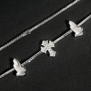 Macro detail of silver S925 moissanite tennis chain necklace with cross and praying hands