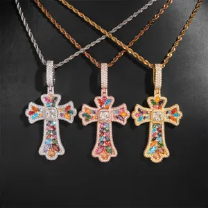 Primer plano de tres colgantes de cruz con piedras de colores en cadenas de cuerda