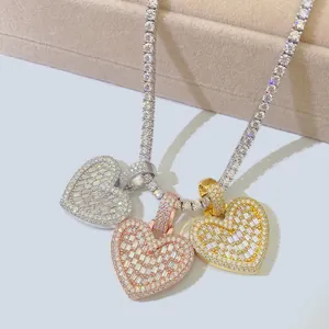 Dettaglio di tre ciondoli hip-hop a forma di cuore in oro e argento con moissanite