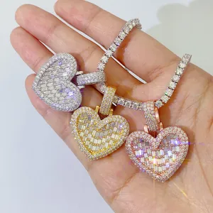 Primo piano di tre pendenti hip-hop in moissanite a cuore in argento, oro e oro rosa