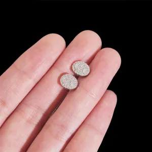 Detalle de pendientes de moissanita en plata 925 sostenidos a mano sobre fondo negro