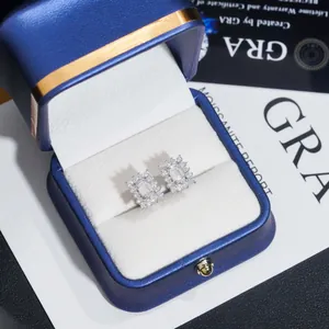 Détail de boucles d'oreilles clous en moissanite taille émeraude dans un écrin bleu de luxe