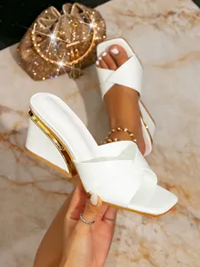 Detailansicht stilvoller weißer Sandalen mit eckiger Zehenpartie und Goldkeilabsatz.
