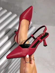 Vista laterale di eleganti scarpe rosse a punta con cinturino e fibbia dorata