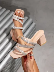 Detailed macro shot of beige square-toe high heel sandals featuring sparkly rhinestone straps.