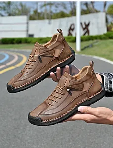 Handheld view of brown casual mid-top leather shoes for men in outdoor setting