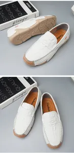 Detailed view of white crocodile pattern men's loafers with soft tan soles.