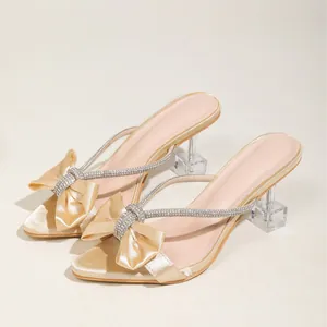 Eleganti sandali con tacco alto color champagne con fiocco di strass e tacco trasparente.