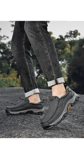 Detail view of men's black slip-on outdoor casual loafers on rocky terrain.