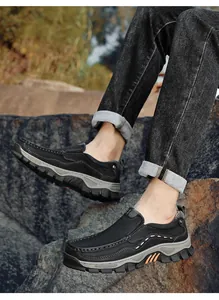 Side view detail of men's black slip-on casual shoes on outdoor rocky terrain