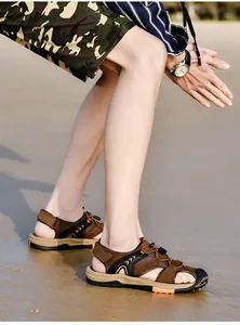 Men's brown closed-toe beach sandals shown in a natural outdoor sandy beach setting.