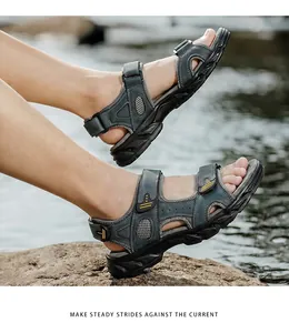 Close-up of men's genuine leather outdoor sandals being worn on a rock near water