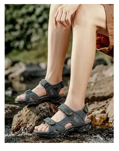 Detailed close-up of men's genuine leather outdoor sandals worn by a model in a natural setting