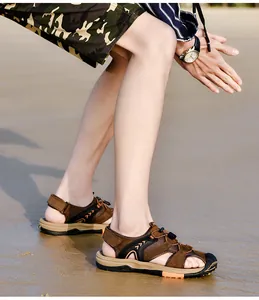 Side view of men's brown closed-toe beach sandals worn on a sunny sandy shore for summer