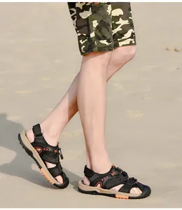 Detail of men's closed-toe beach sandals being worn on sand with camouflage shorts