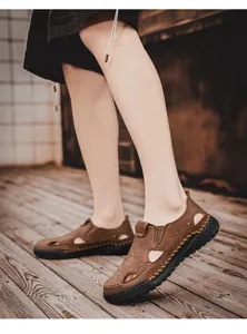 Macro detail view of brown leather hollow-out breathable sandals worn on wooden floor
