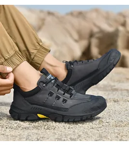 Primo piano di scarpe da trekking grigie da uomo indossate su terreno roccioso di giorno.
