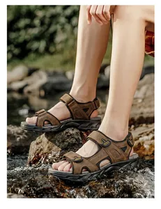 Detailed view of brown leather outdoor sandals worn by a male model near water.