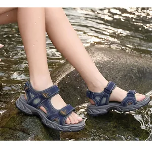 Close-up view of navy blue men's leather outdoor sandals worn on wet rocks in a stream