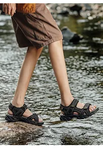 Macro detail of men's black leather outdoor sandals worn in a natural river setting