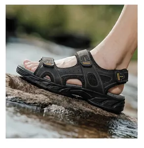 Side view of black men's genuine leather outdoor sandals on a rocky stream bank.