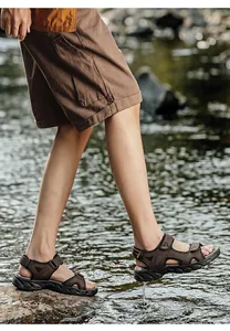 Side view detail of men's brown leather sandals worn in a natural water stream