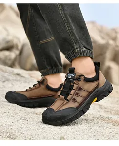 Primo piano di scarpe da trekking in pelle marrone da uomo su un terreno roccioso